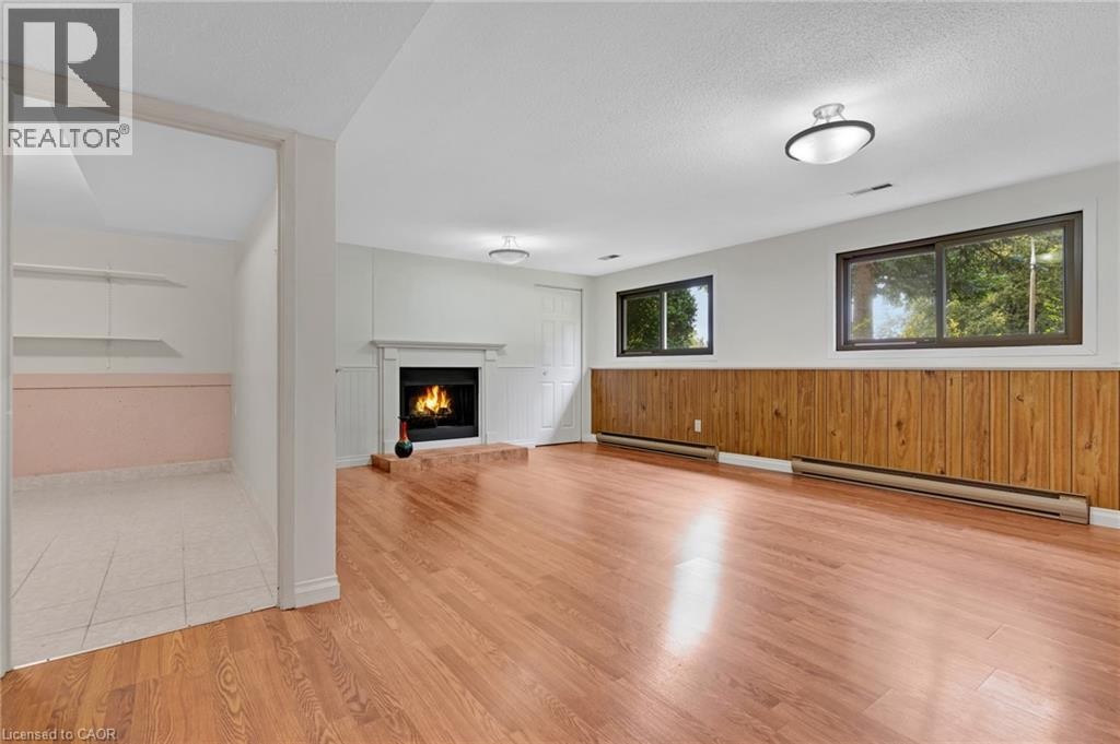 Wood-finish flooring, a fireplace with a white mantel, and wood paneling - 7 Underhill Crescent, Kitchener, ON