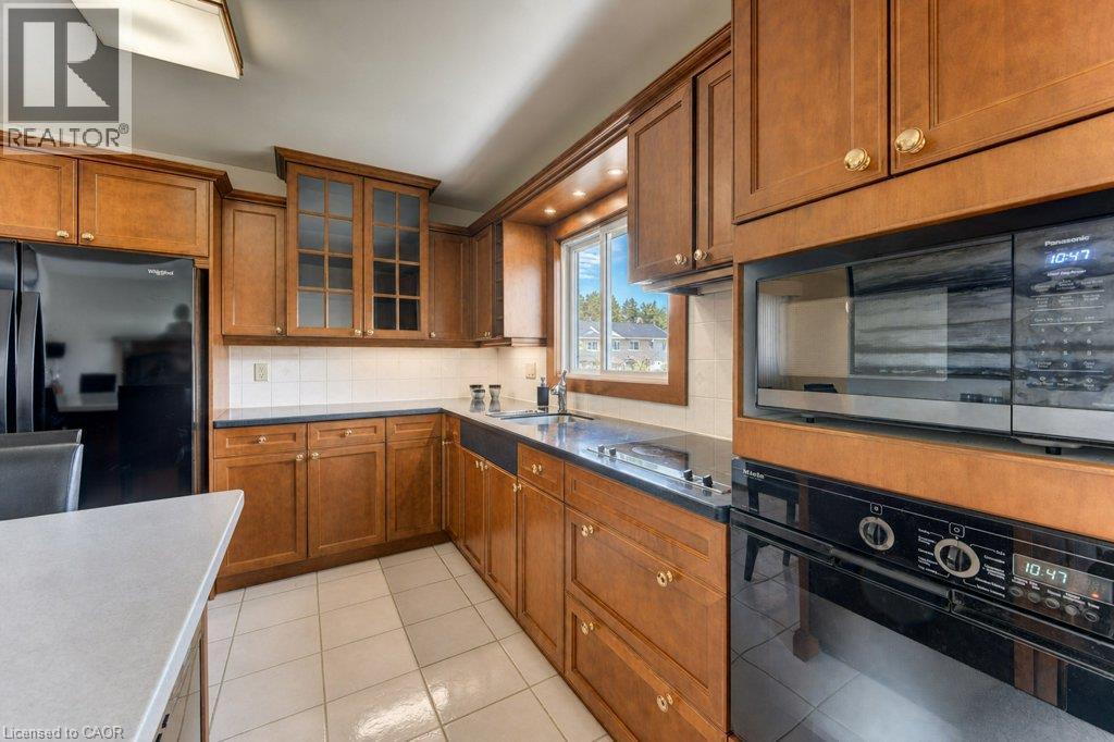 Kitchen featuring wood-finish cabinetry, integrated appliances, and a tiled backsplash - 238 Mcgarry Drive, Kitchener, ON