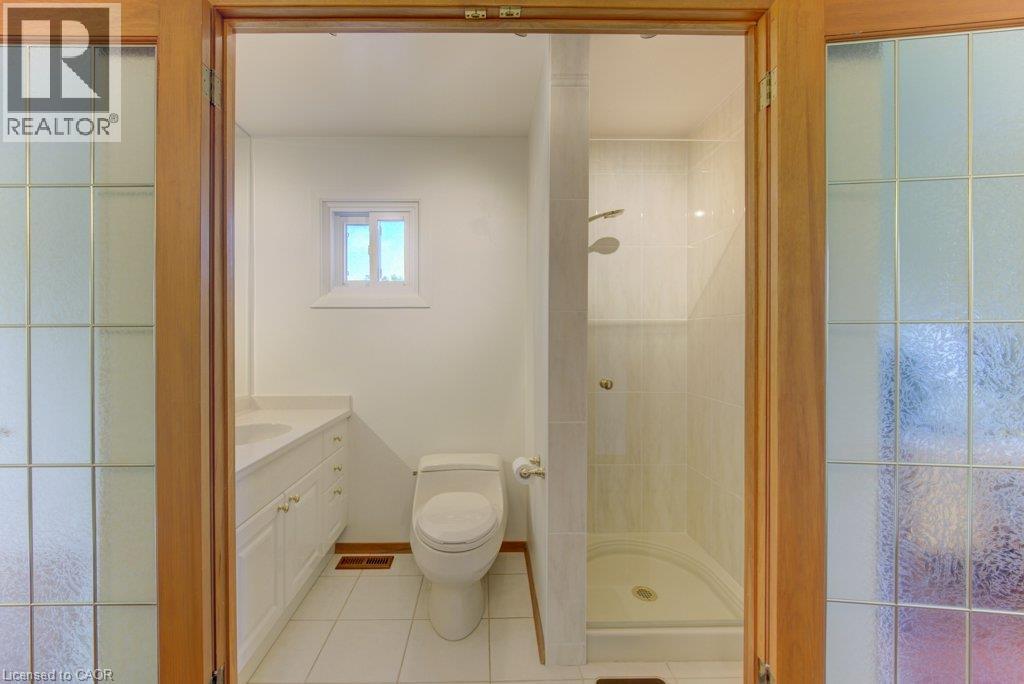 Bathroom with tile flooring, white vanity with dual sinks, and a glass-enclosed shower - 238 Mcgarry Drive, Kitchener, ON