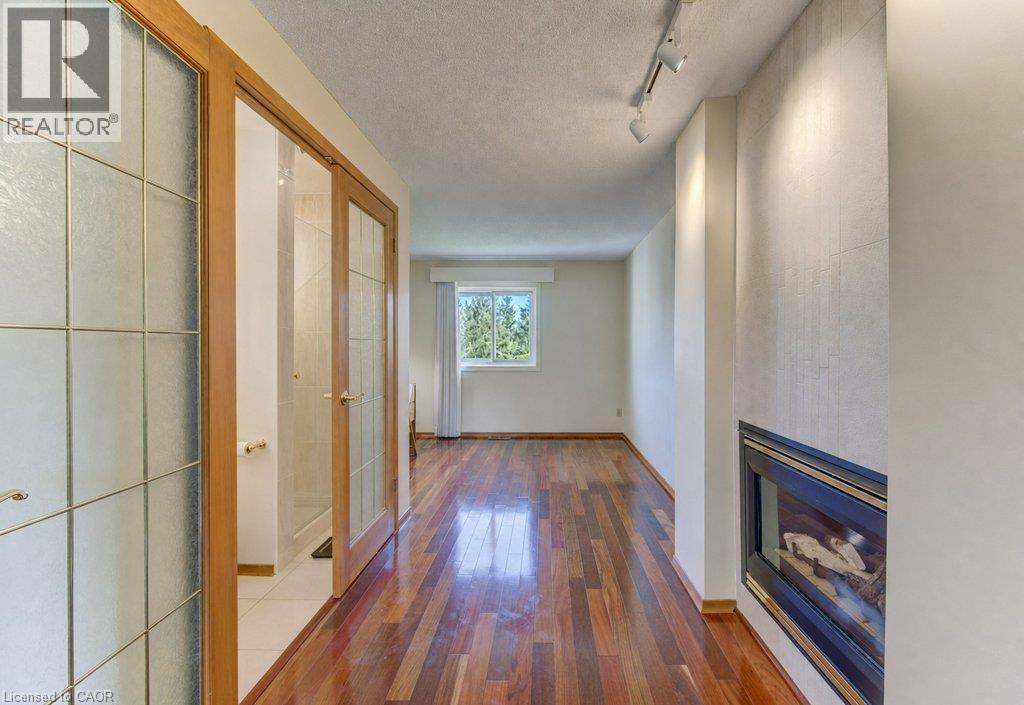 Wood-finish flooring, recessed fireplace, track lighting, frosted glass doors with wood framing, and a window with a white frame - 238 Mcgarry Drive, Kitchener, ON