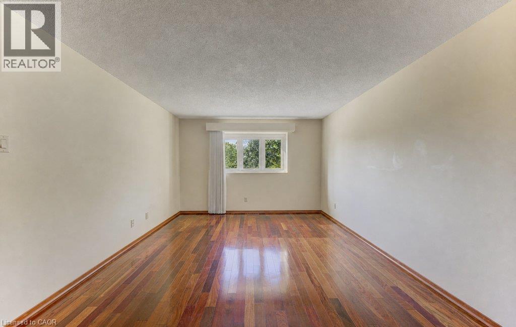 Hardwood-style flooring with a natural finish, white painted walls, and a window with a sheer curtain - 238 Mcgarry Drive, Kitchener, ON