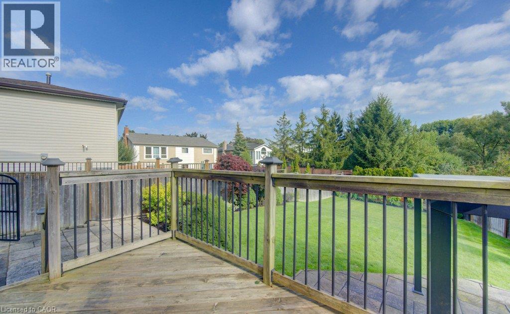 Wood-finish deck with black spindle railing, stone paver patio, and grass lawn - 238 Mcgarry Drive, Kitchener, ON