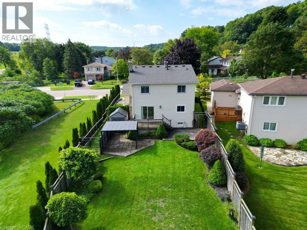 Expansive backyard siding onto a greenbelt, featuring a manicured lawn, established landscaping, a paved patio area, and a wood deck - 238 Mcgarry Drive, Kitchener, ON
