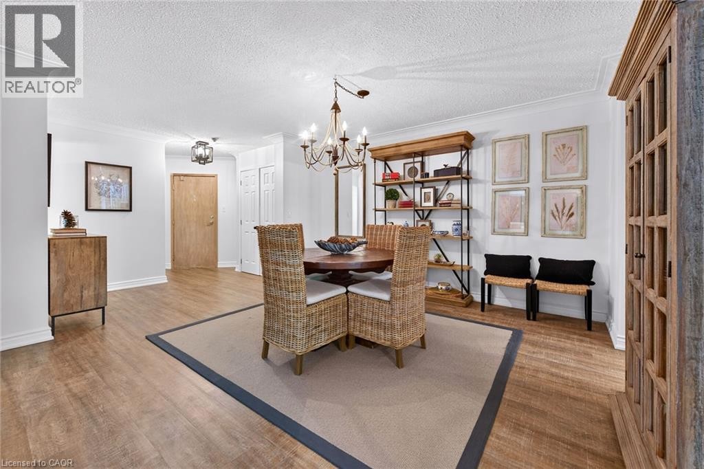 Open dining area featuring wood-finish flooring and crown molding - 1237 North Shore Boulevard Unit# 405, Burlington, ON