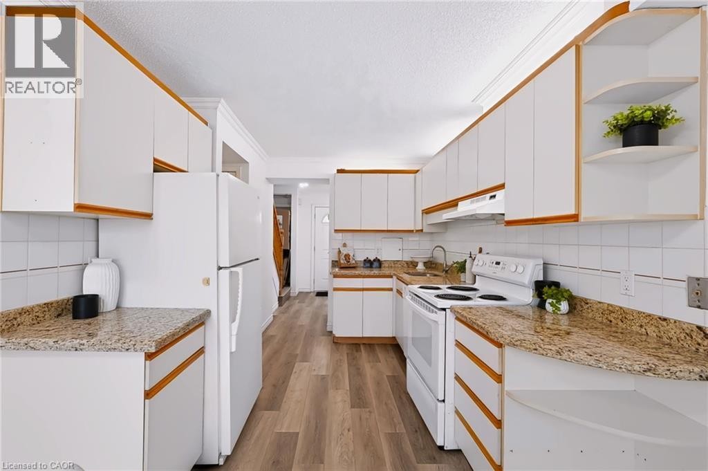 Kitchen featuring ample white cabinetry, wood-finish flooring, white tile backsplash, and granite countertops - 121 University Avenue E Unit# 102, Waterloo, ON