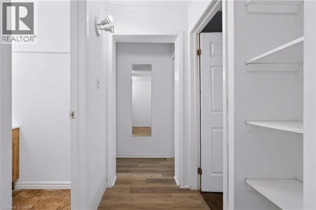 Interior hallway with wood-finish flooring, white walls, and built-in shelving - 121 University Avenue E Unit# 102, Waterloo, ON