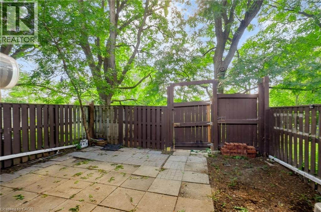 Paved patio area with a privacy fence and a wooden gate - 121 University Avenue E Unit# 102, Waterloo, ON