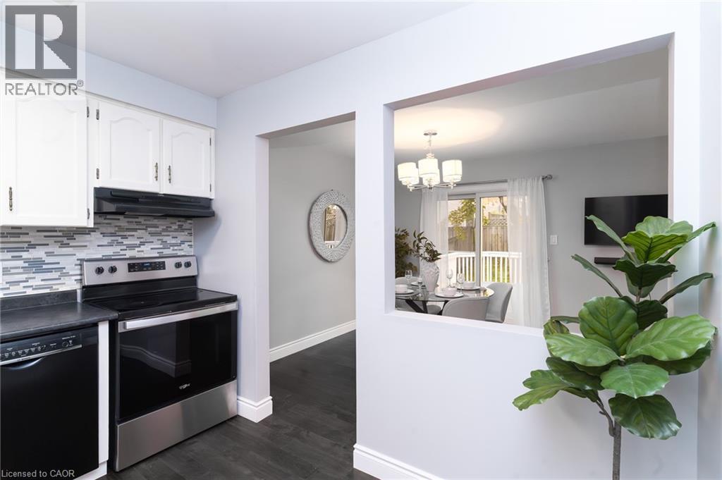 Kitchen with white cabinetry, mosaic tile backsplash, stainless steel range, and black dishwasher - 543 Drummerhill Crescent, Waterloo, ON