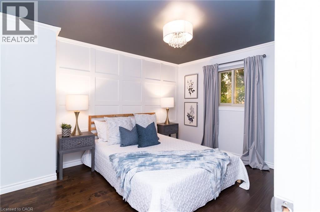 Wood-finish flooring, accent wall with panel molding, single window with roller shade, and a flush-mount crystal chandelier - 543 Drummerhill Crescent, Waterloo, ON
