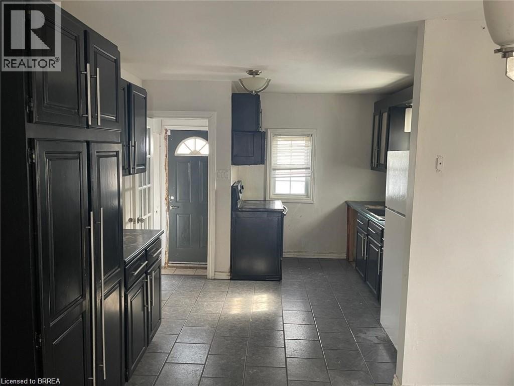 Kitchen featuring dark cabinetry with silver-tone hardware, a window with blinds, and tile flooring - 258 Wellington Road, London, ON