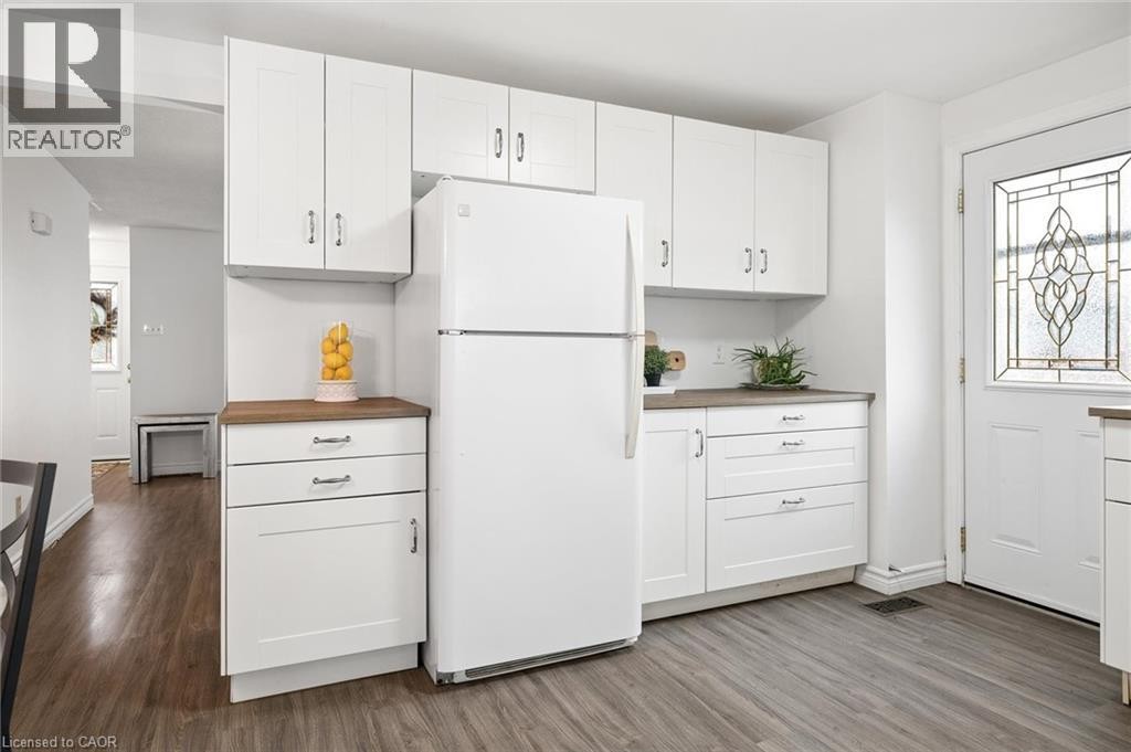 White cabinetry with silver-tone hardware, wood-finish flooring, and a door featuring decorative glass inlay - 76 Cluthe Crescent, Kitchener, ON