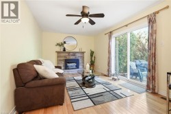 Hardwood flooring, a stone-faced fireplace, a ceiling fan, and sliding glass doors leading to an outdoor space -