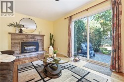 Stone-clad fireplace with hearth, wood-finish flooring, and sliding glass door to an exterior paver patio -