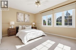 Carpeted room featuring two large windows with roller shades and a ceiling fan with integrated lighting -