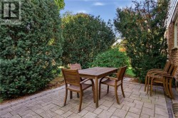 Stone paver patio featuring mature perimeter shrubbery and brick exterior detailing -