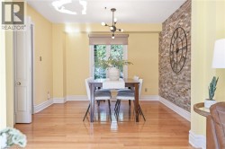 Bright dining room showcasing warm yellow walls, hardwood flooring, and abundant natural light from large windows -