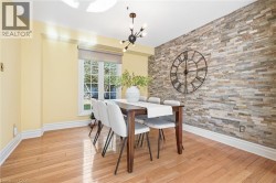 Hardwood flooring, accent wall with stacked stone finish, large window, contemporary chandelier, and white trim -