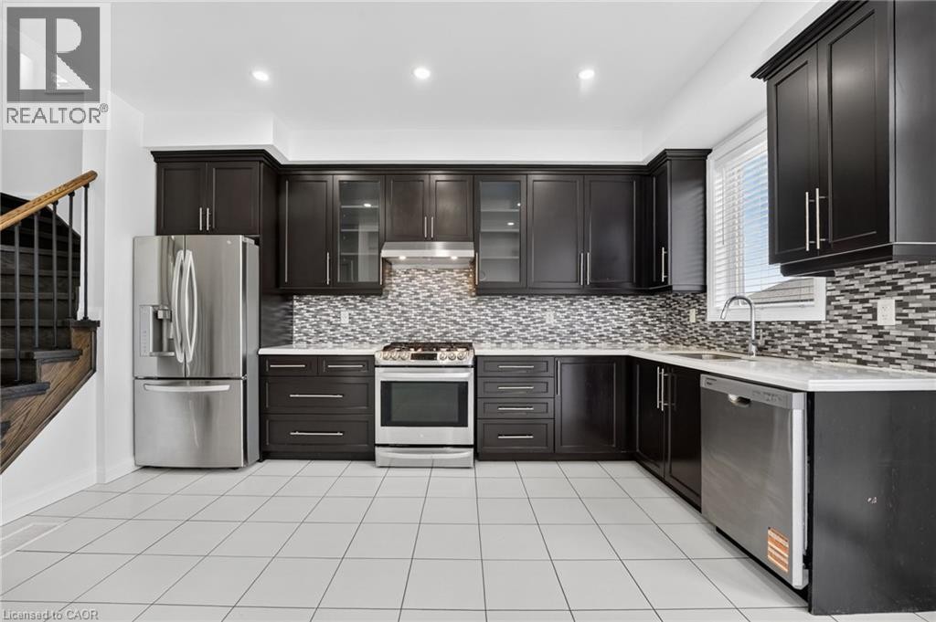 Modern kitchen featuring dark cabinetry with glass-front upper doors, stainless steel appliances including a French-door refrigerator and slide-in range, mosaic tile backsplash, quartz countertops, an - 1169 E Garner Road E Unit# 66, Ancaster, ON