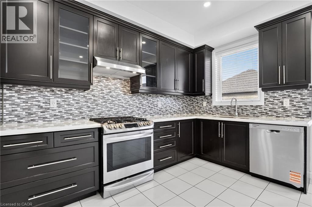 Dark wood cabinetry with glass-front accents, stainless steel appliances, mosaic tile backsplash, white countertops, and tiled flooring - 1169 E Garner Road E Unit# 66, Ancaster, ON