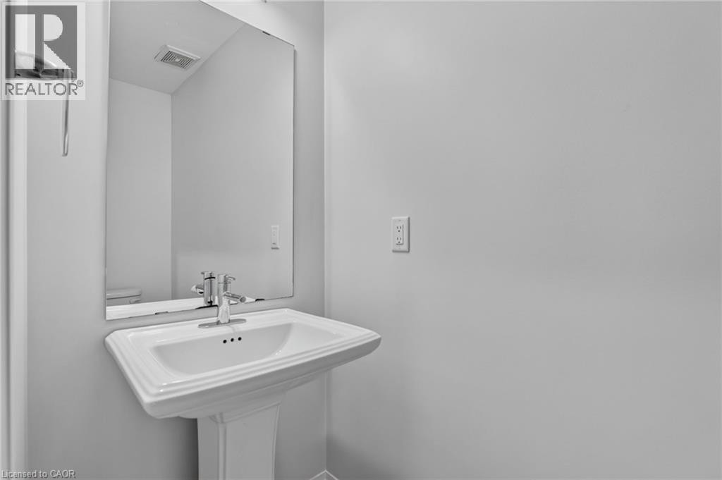 White pedestal sink with chrome faucet, complemented by a rectangular wall-mounted mirror - 1169 E Garner Road E Unit# 66, Ancaster, ON
