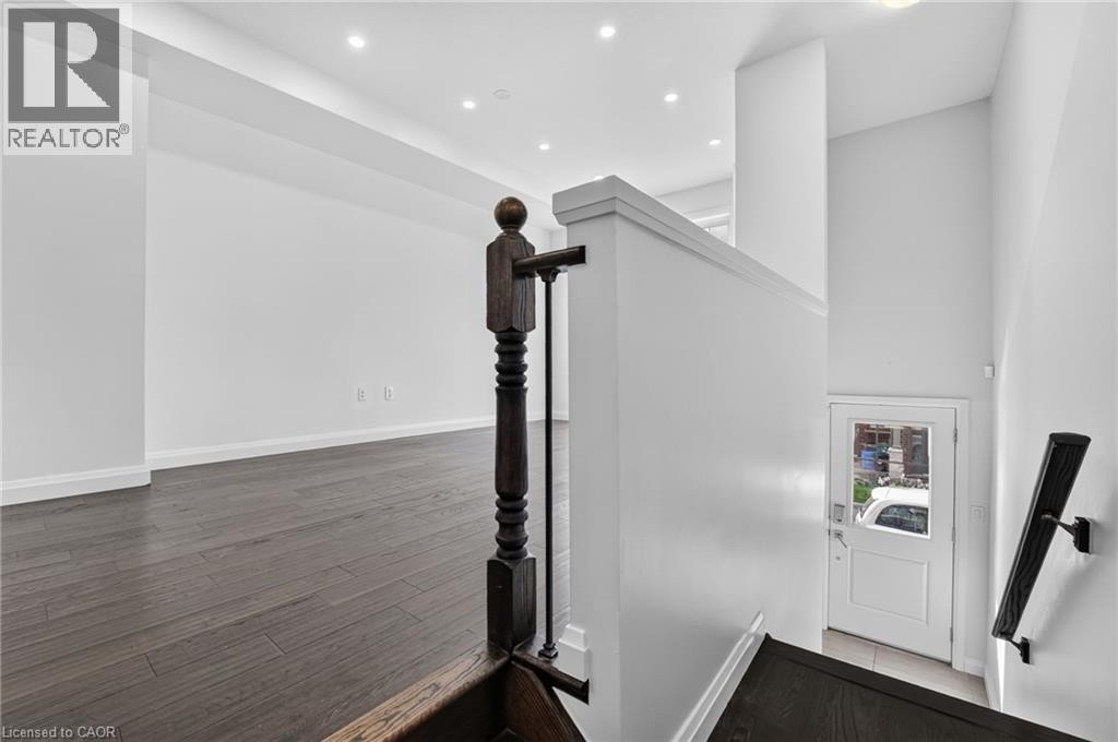 Wood-finish flooring, white walls, dark wood newel post, recessed lighting, and a white door with glass panel - 1169 E Garner Road E Unit# 66, Ancaster, ON