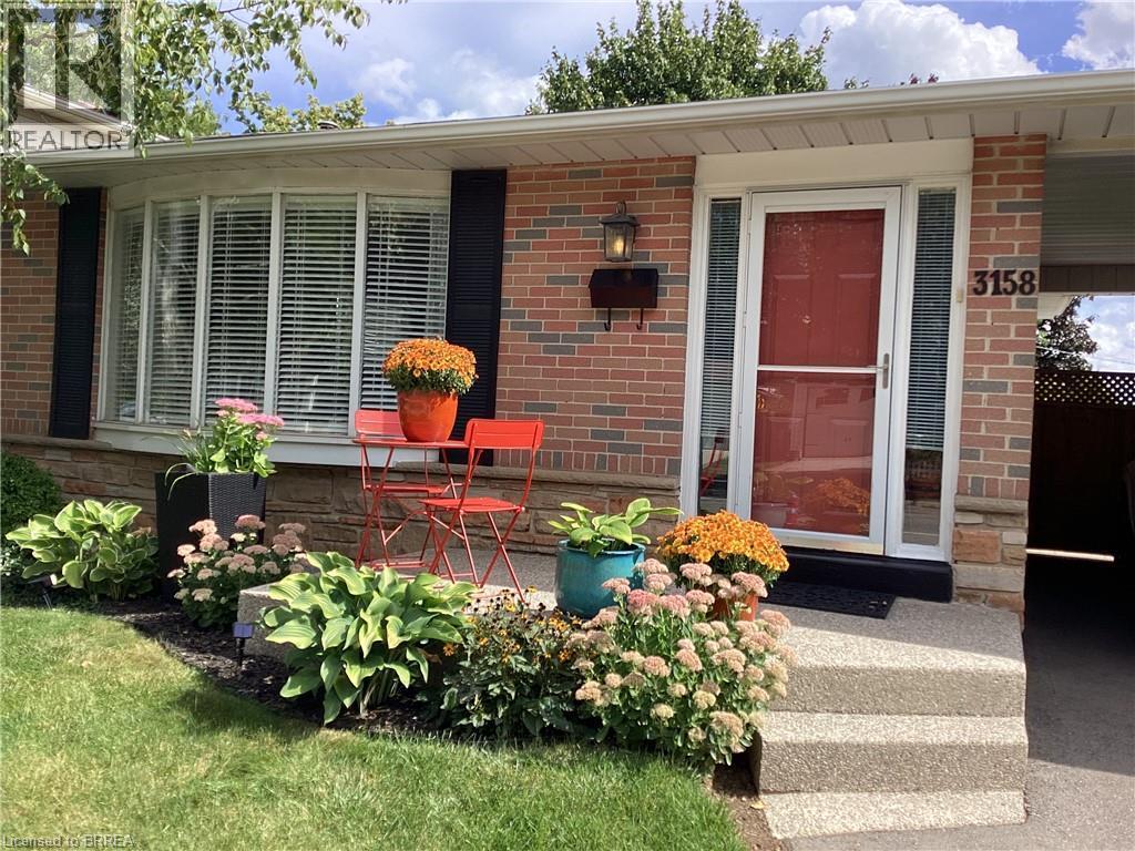 Brick exterior with stone accents, bay window, front entryway with side lights, and concrete steps - 3158 Palmer Drive, Burlington, ON