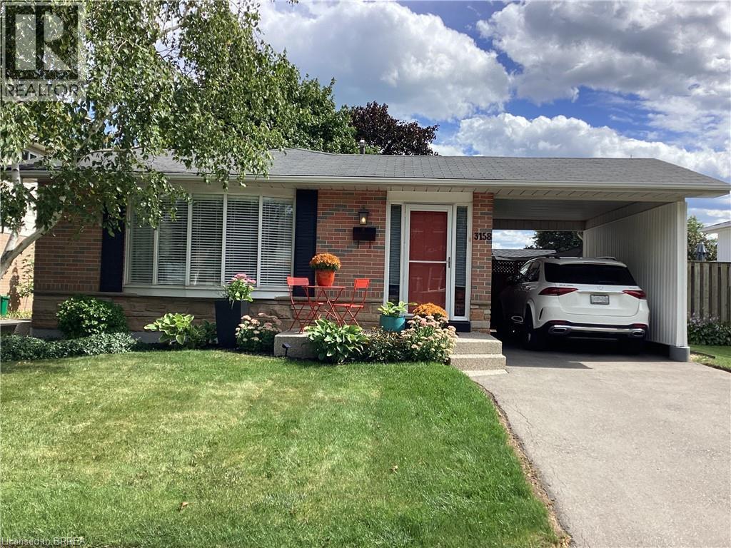 Brick exterior with dark shutters, covered carport, front bay window, and manicured landscaping - 3158 Palmer Drive, Burlington, ON
