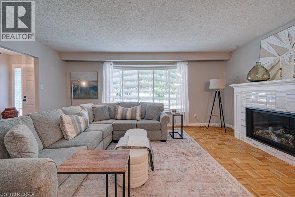 Hardwood flooring, white brick fireplace with mantel, large window with blinds, and a doorway - 3158 Palmer Drive, Burlington, ON