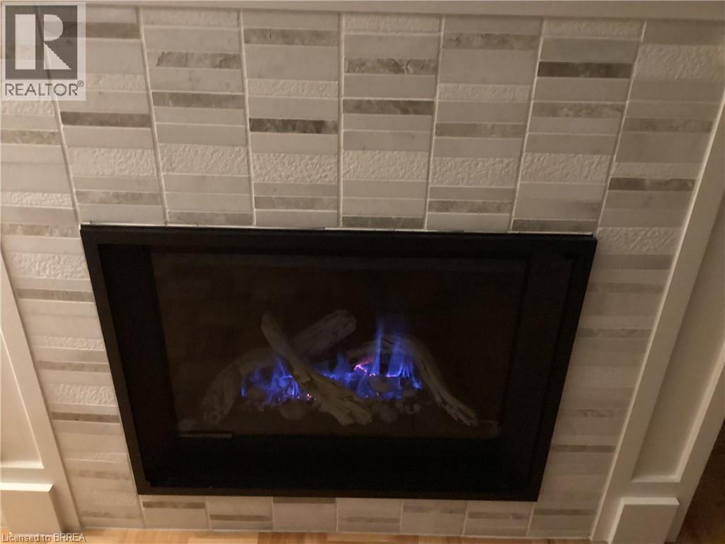Fireplace with stone tile surround, integrated gas logs, and black trim - 3158 Palmer Drive, Burlington, ON