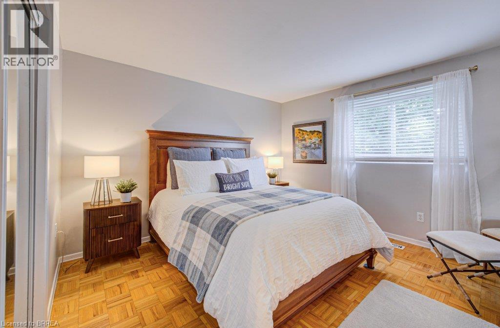 Hardwood parquet flooring, light gray wall tones, window with white blinds, white sheer curtains, and mirrored closet doors - 3158 Palmer Drive, Burlington, ON