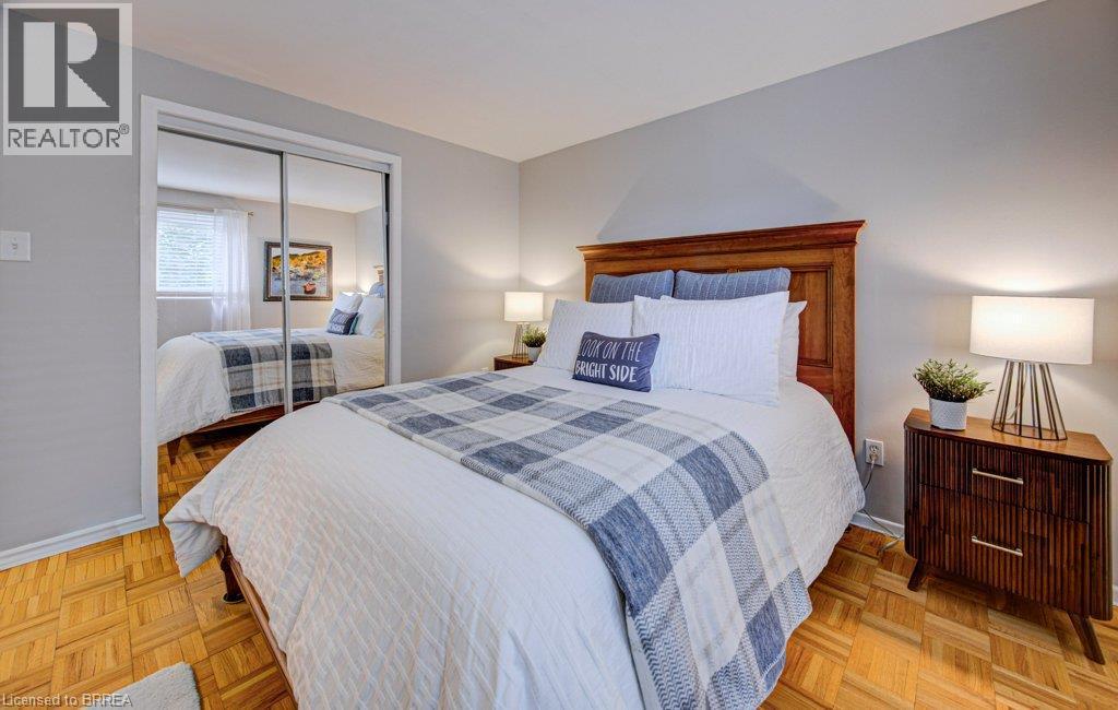 Hardwood parquet flooring, neutral wall paint, mirrored sliding closet doors, and wood-finish bed frame - 3158 Palmer Drive, Burlington, ON