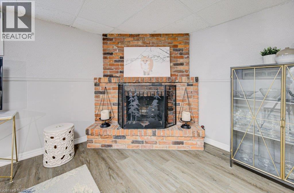 Brick fireplace with a black metal screen and wood-finish flooring - 3158 Palmer Drive, Burlington, ON