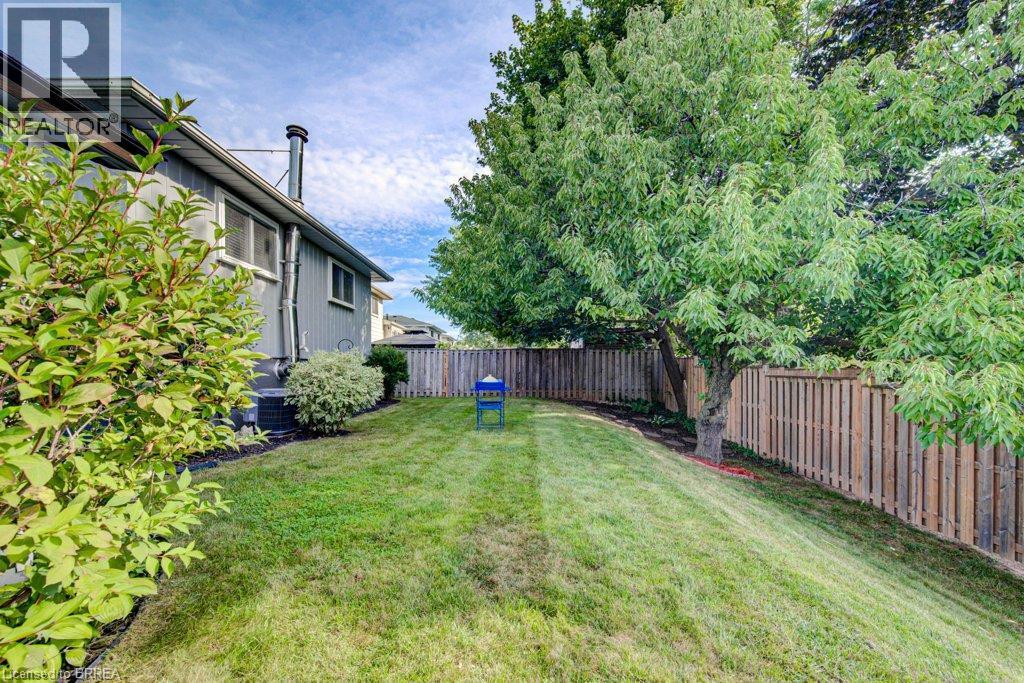 Expansive grassy yard with mature trees, established shrubbery, and a wood privacy fence - 3158 Palmer Drive, Burlington, ON