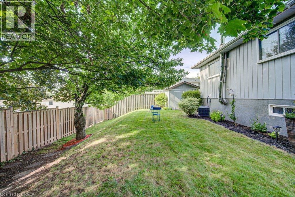 Expansive backyard featuring a manicured lawn, established shade tree, and wood privacy fencing - 3158 Palmer Drive, Burlington, ON