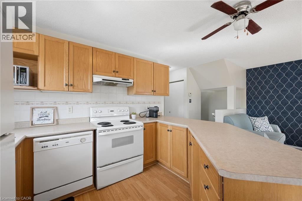 Light wood-finish cabinetry, white appliances, patterned tile backsplash, and a ceiling fan with light fixture - 67 Apple Tree Drive, Kitchener, ON