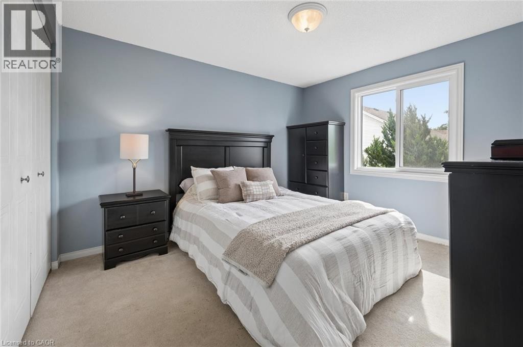 Built-in closet with bifold doors, window with white trim, wall-mounted ceiling light fixture, and plush carpeting - 67 Apple Tree Drive, Kitchener, ON