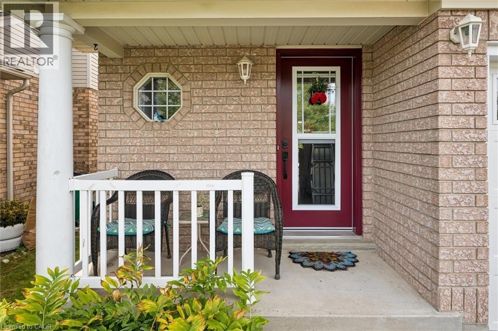 Brick exterior with a covered porch featuring a white column, white railing, and an octagonal window - 67 Apple Tree Drive, Kitchener, ON