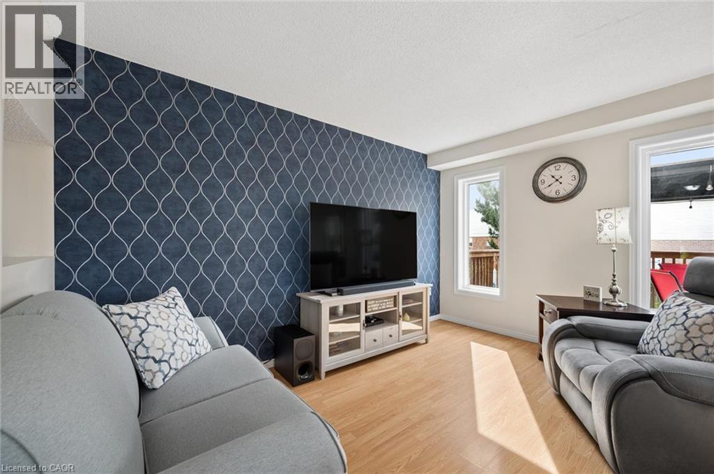 Accent wall featuring a geometric pattern, two windows, and wood-finish flooring - 67 Apple Tree Drive, Kitchener, ON