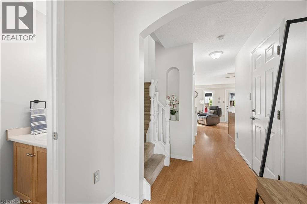 Wood-finish flooring throughout, arched entryway, staircase with white spindles, built-in wall niche, and panel interior door - 67 Apple Tree Drive, Kitchener, ON