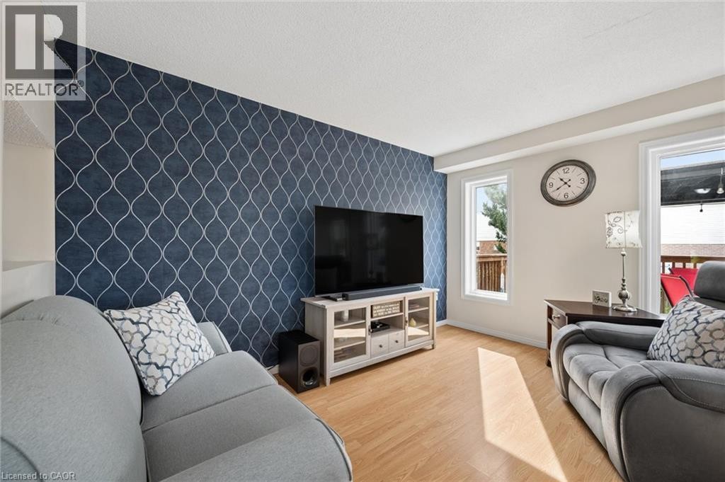Accent wall featuring a geometric pattern, two windows, and wood-finish flooring - 67 Apple Tree Drive, Kitchener, ON