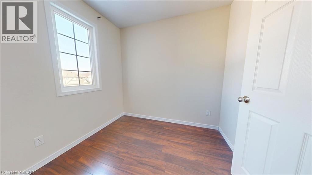 Wood-finish flooring, neutral wall tones, white trim, and a multi-pane window - 11 Sorrento Street, Kitchener, ON