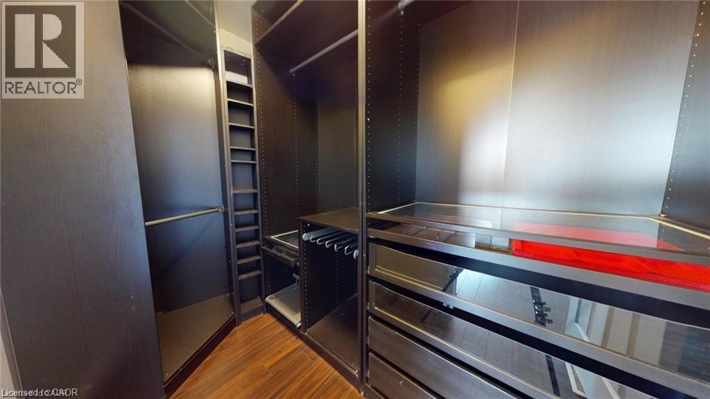 Built-in custom closet system featuring dark wood-finish cabinetry, extensive shelving, hanging rods, and integrated drawers with reflective panels - 11 Sorrento Street, Kitchener, ON