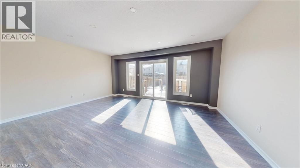 Wood-finish flooring, recessed ceiling lighting, and a sliding glass door with two adjacent windows - 11 Sorrento Street, Kitchener, ON