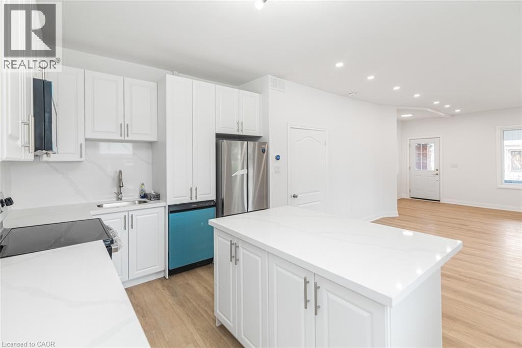 Kitchen featuring white cabinetry, stainless steel appliances, white countertops, and a central island - 90 Belview Avenue, Hamilton, ON