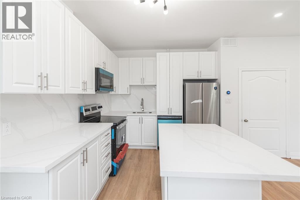 White shaker-style cabinetry with chrome hardware, white stone countertops, stainless steel appliances, and wood-finish flooring - 90 Belview Avenue, Hamilton, ON