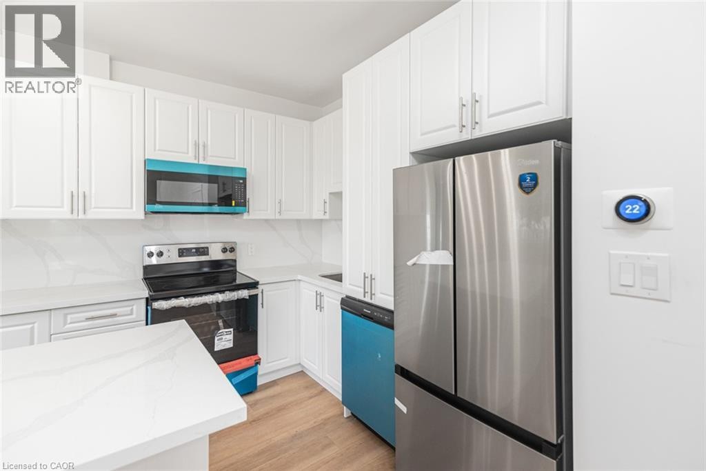 White shaker cabinetry, stainless steel appliances, light wood-finish flooring, white countertops, and a smart thermostat - 90 Belview Avenue, Hamilton, ON
