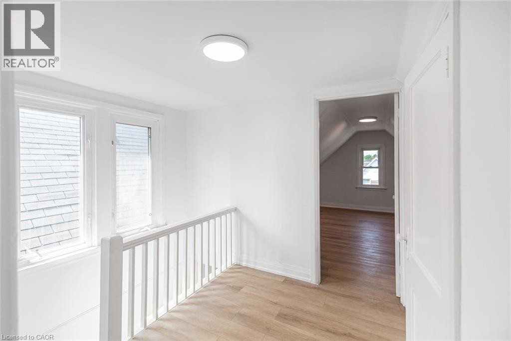 Wood-finish flooring throughout, white painted walls, white trim, recessed lighting, and white baluster railing - 90 Belview Avenue, Hamilton, ON