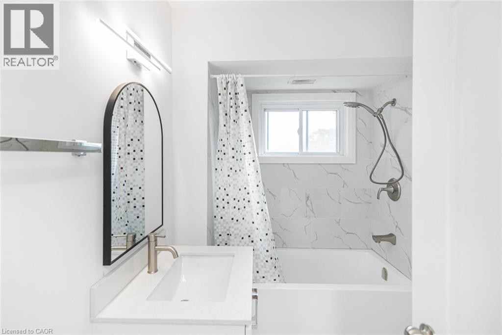 White vanity with an integrated rectangular sink, brushed nickel faucet, and an arched wall mirror - 90 Belview Avenue, Hamilton, ON