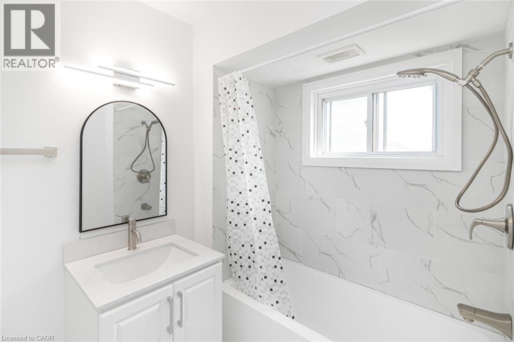 White bathroom vanity with a single basin, brushed nickel faucet, and an arched mirror - 90 Belview Avenue, Hamilton, ON