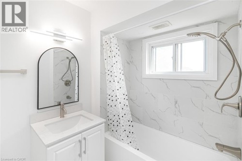 White bathroom vanity with a single basin, brushed nickel faucet, and an arched mirror - 90 Belview Avenue, Hamilton, ON 